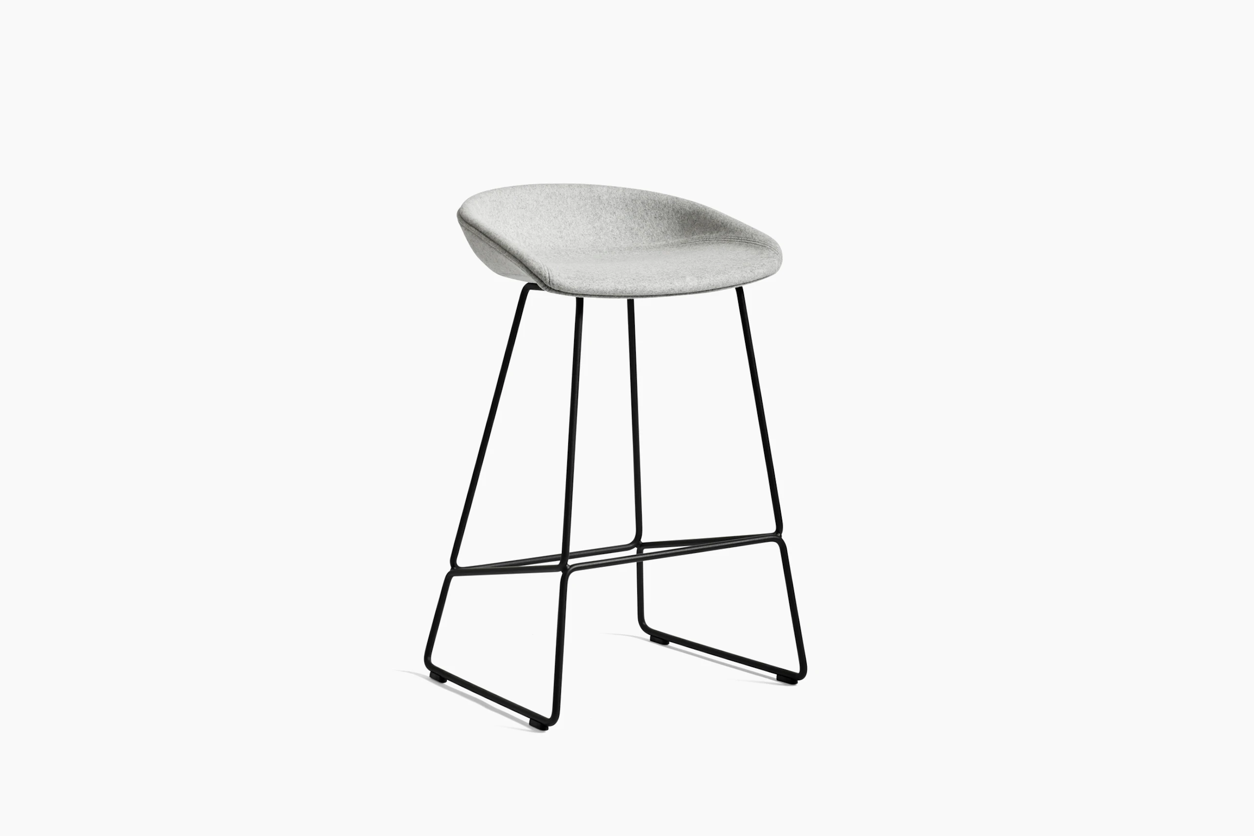 Grey upholstered About A Stool with metal base, viewed at an angle.