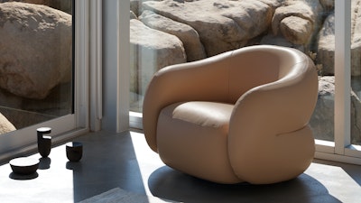 A Soffi Swivel Chair by DWR in tan leather next to a sunny window.