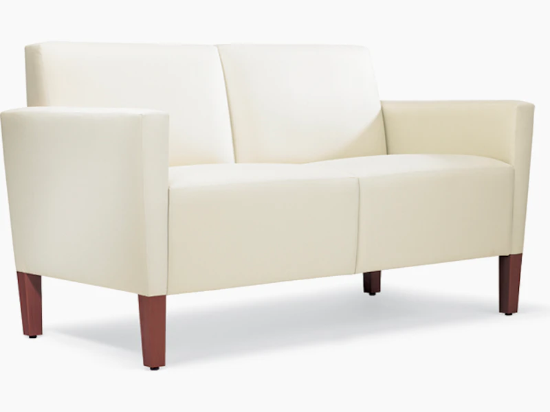 A three-quarter view of a Brava Classic Lounge Settee with white textile and upholstered arm caps.