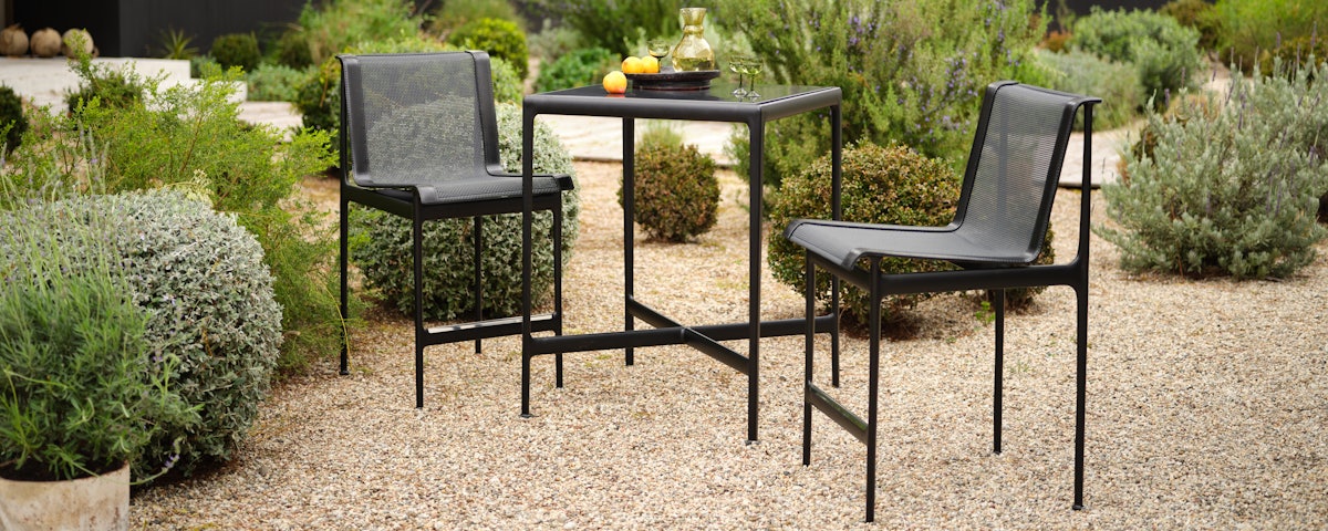 1966 Armless Stool and 1966 High Table in a courtyard setting