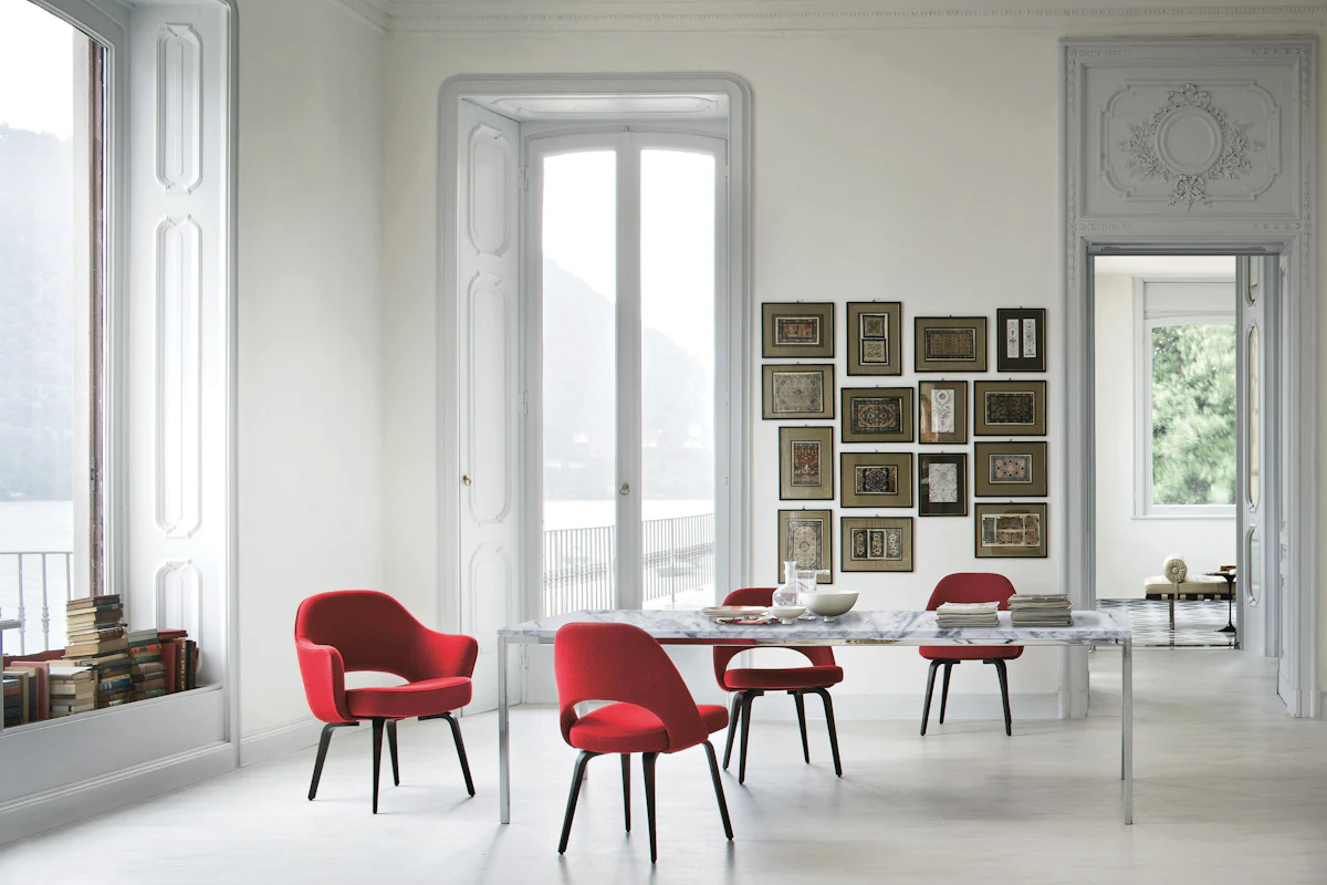 Bright white dining room with red chairs and gallery wall, marble table in foreground