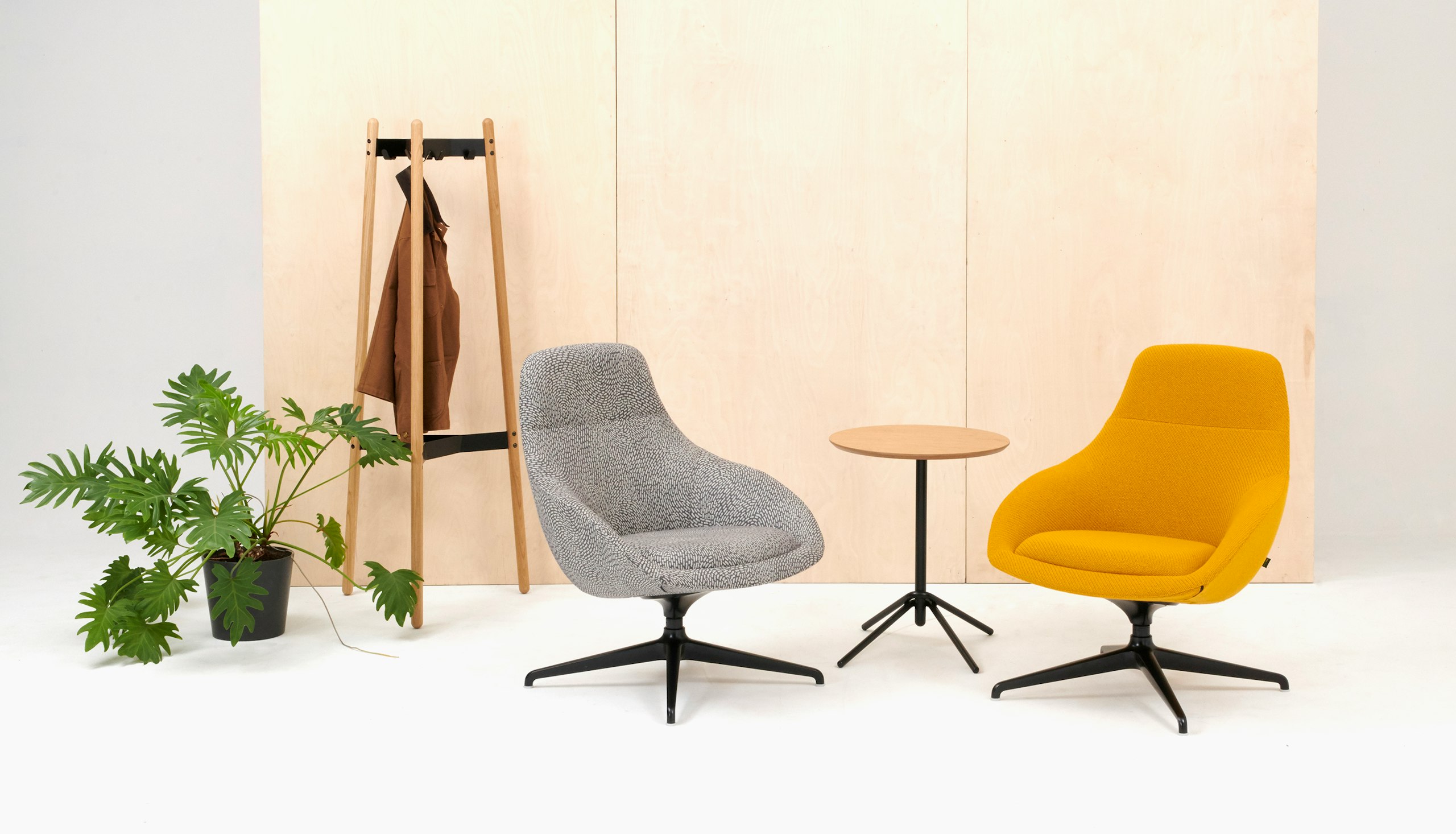 A Hudson Coat Stand with oak dowel legs and black metal supports next to 2 Always chairs and a table.