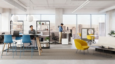 Two individuals working in a group office setting furnished with Herman Miller Passport Work Tables, NaughtOne Rhyme and Muuto Oslo Lounge boost chairs, and Herman Miller OE1 and NaughtOne Morse Bar Tables