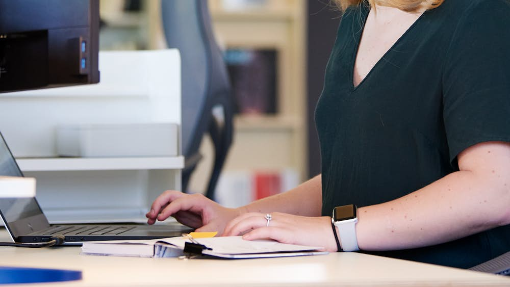  Woman typing on laptop sitting in Cosm Chair