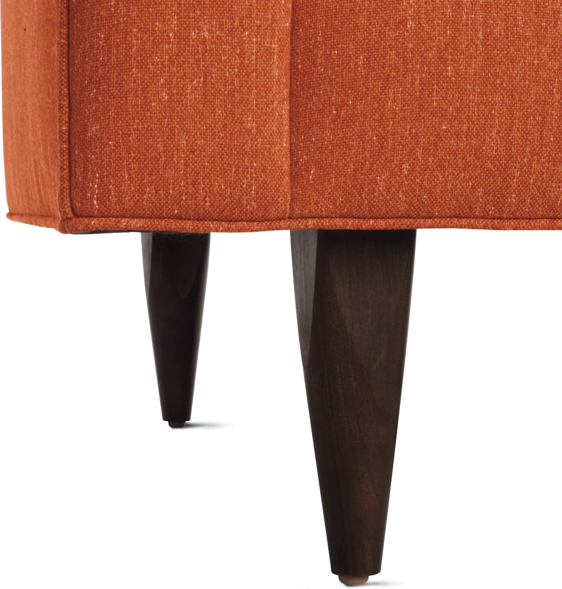 Close-up of orange mid-century modern sofa legs and bottom edge.