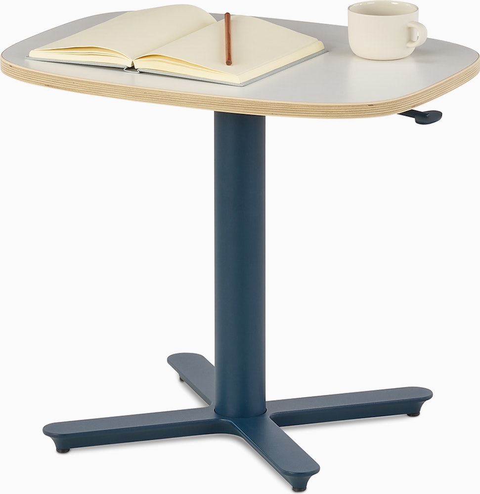 Small Passport Work Table with white surface, plywood edge and dark blue base shown on glides.