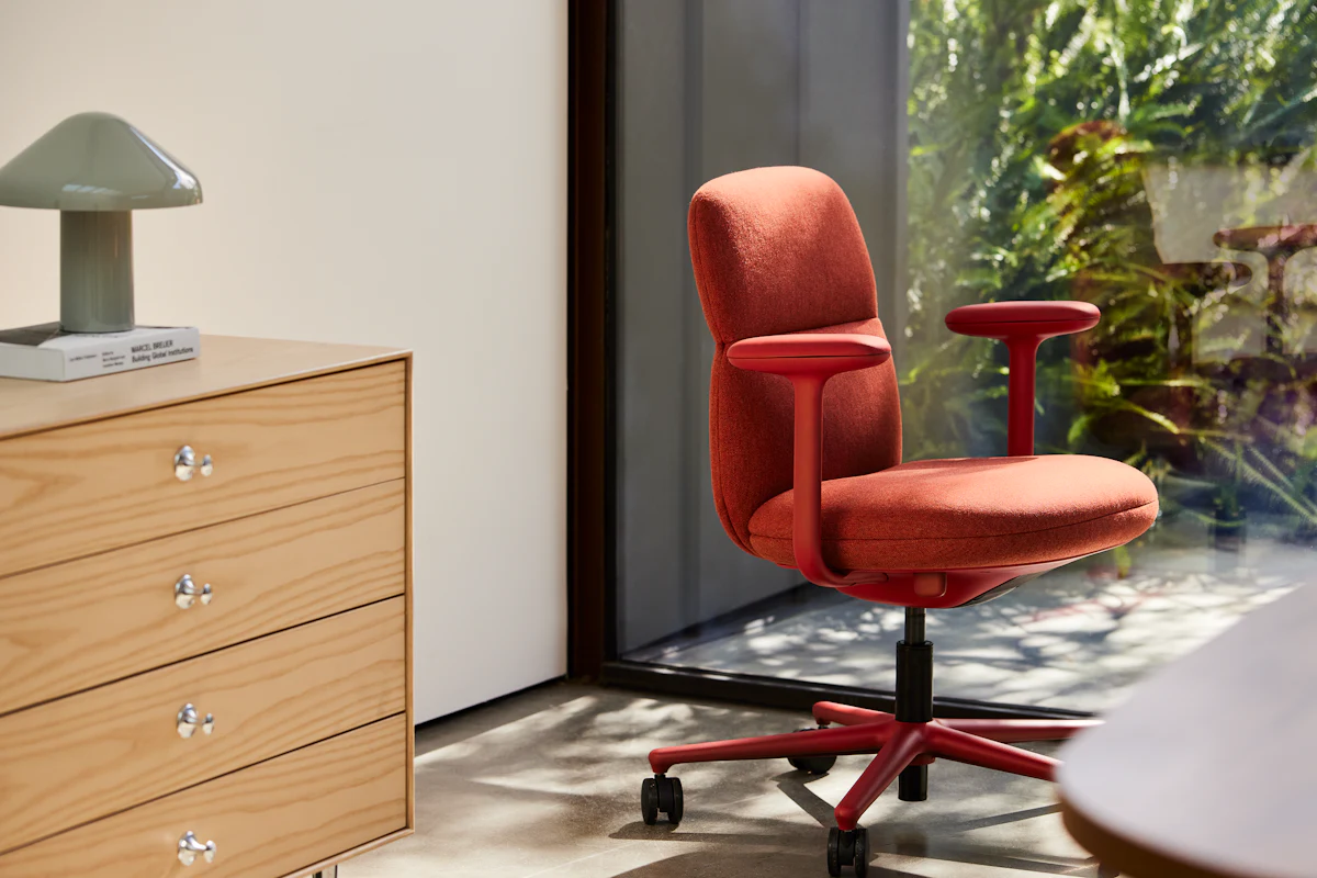 Red office chair in front of a desk by window in a modern office