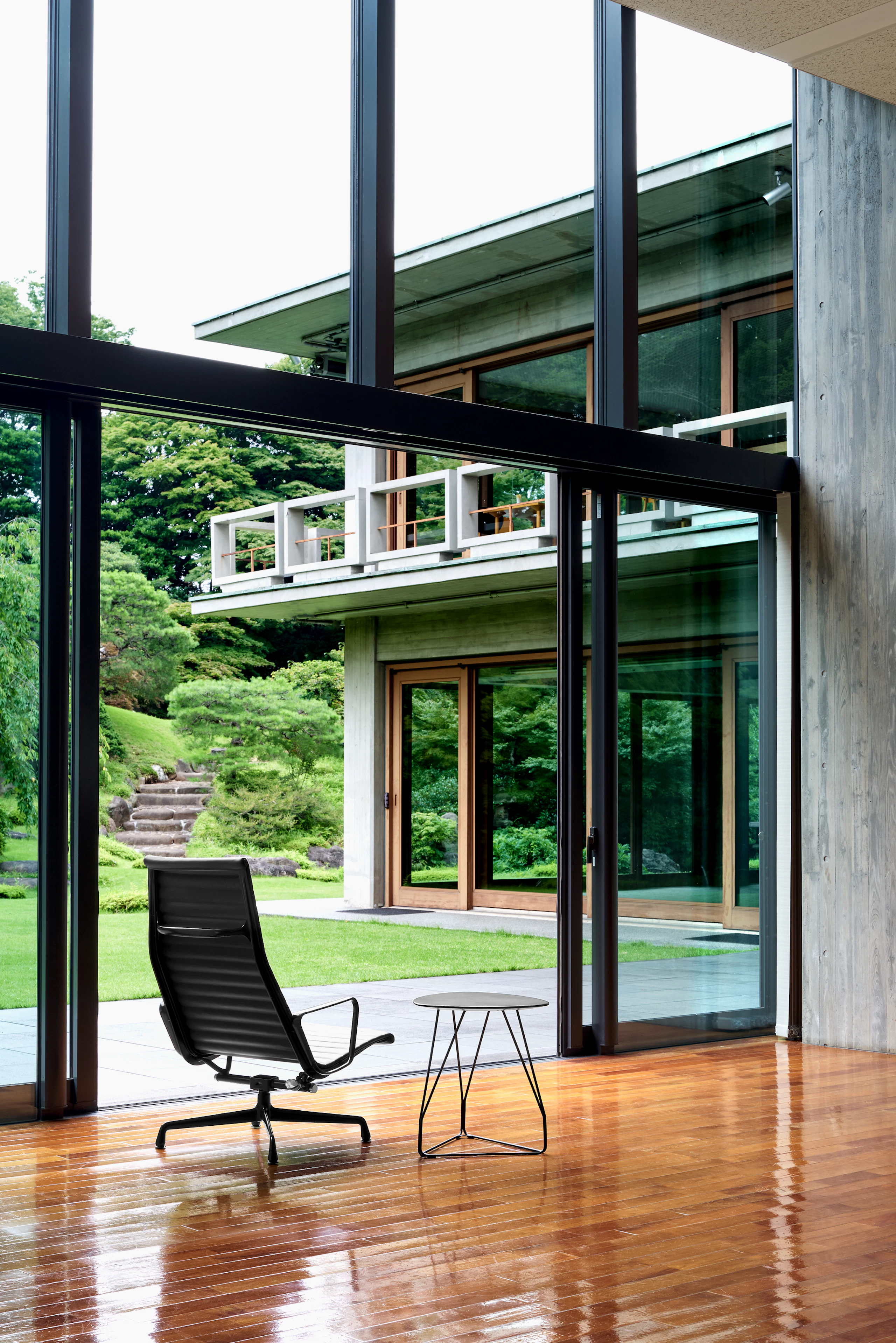 An Eames Aluminum Group Lounge Chair in black frame with a Polygon Wire Table.