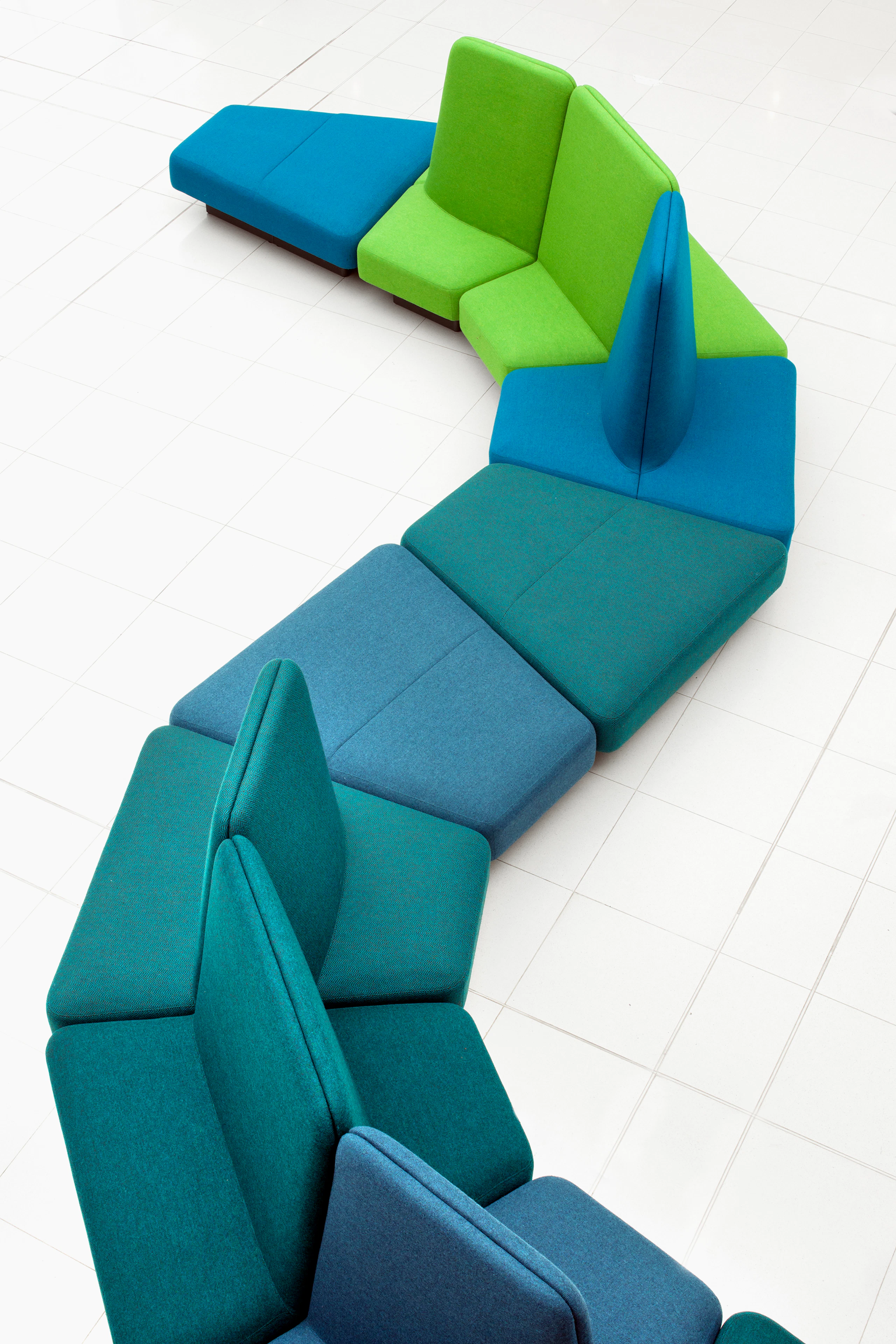 An overhead view of a Rhyme Modular Seating arrangement with shades of blue and green snaking across a white tiled floor.