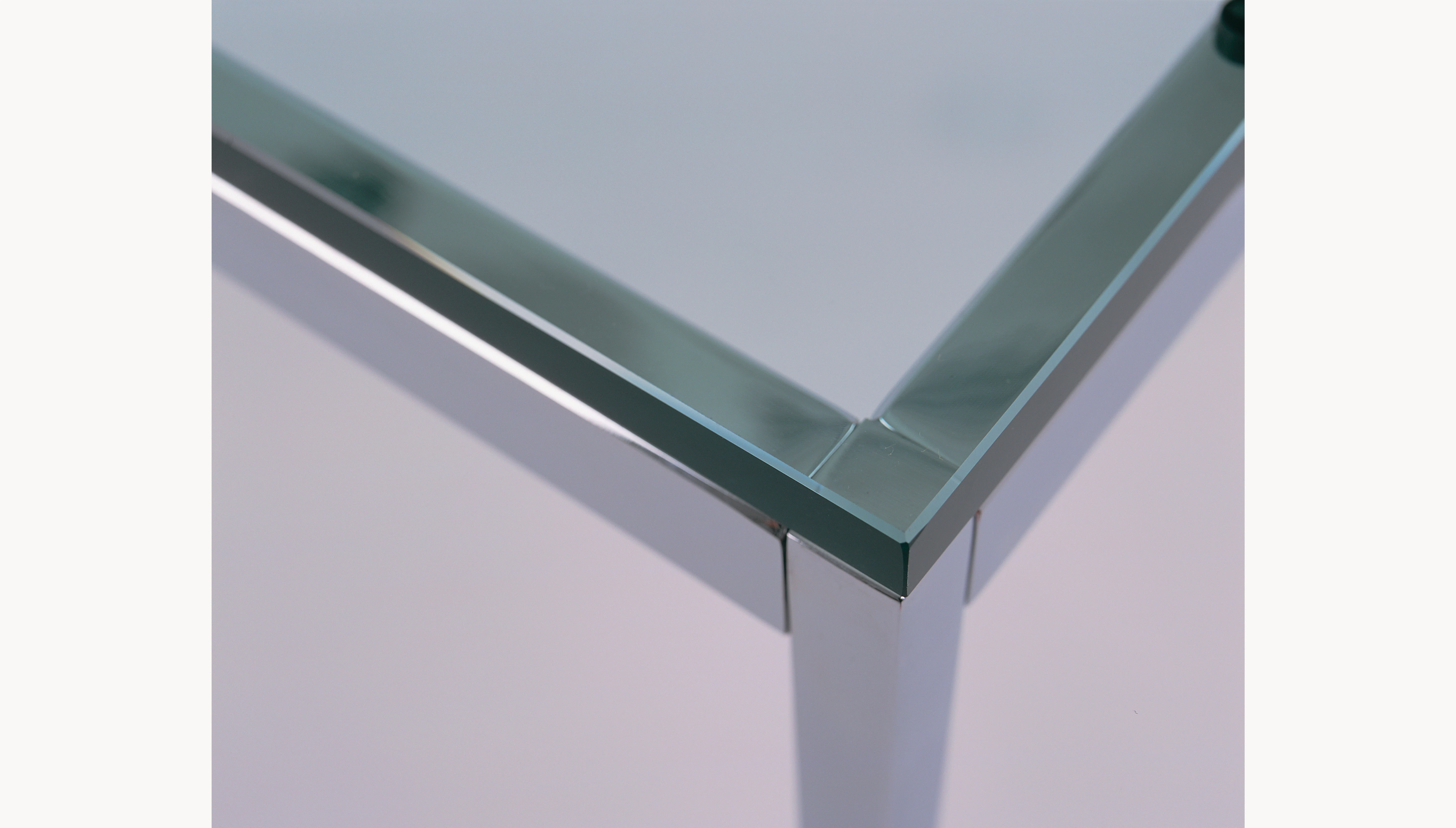 Close-up of the chrome frame connecting to the glass tabletop.