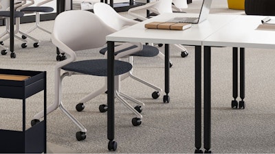 A laptop and book sitting on a black and white table that features white Herman Miller Fuld Nesting chairs dark blue seats next to a Herman Miller OE1 storage trolley