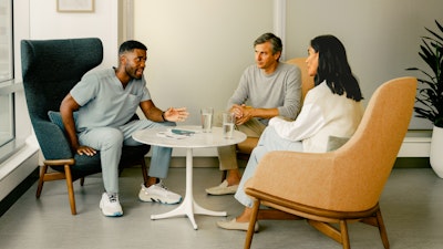Male nurse consulting with a female patient and her male family member in a casual setting.