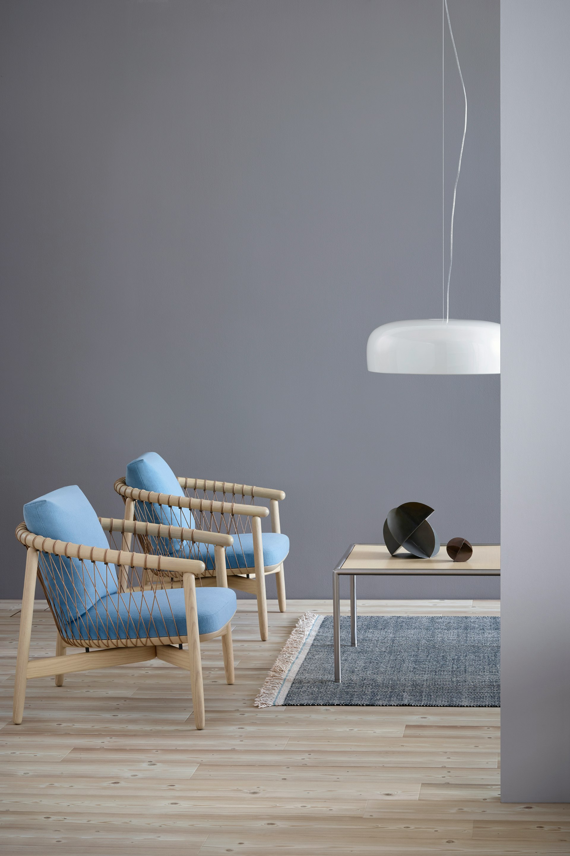 Two Crosshatch lounge chairs with light blue fabric and light wood frames, positioned next to a rectangular Full Round coffee table.