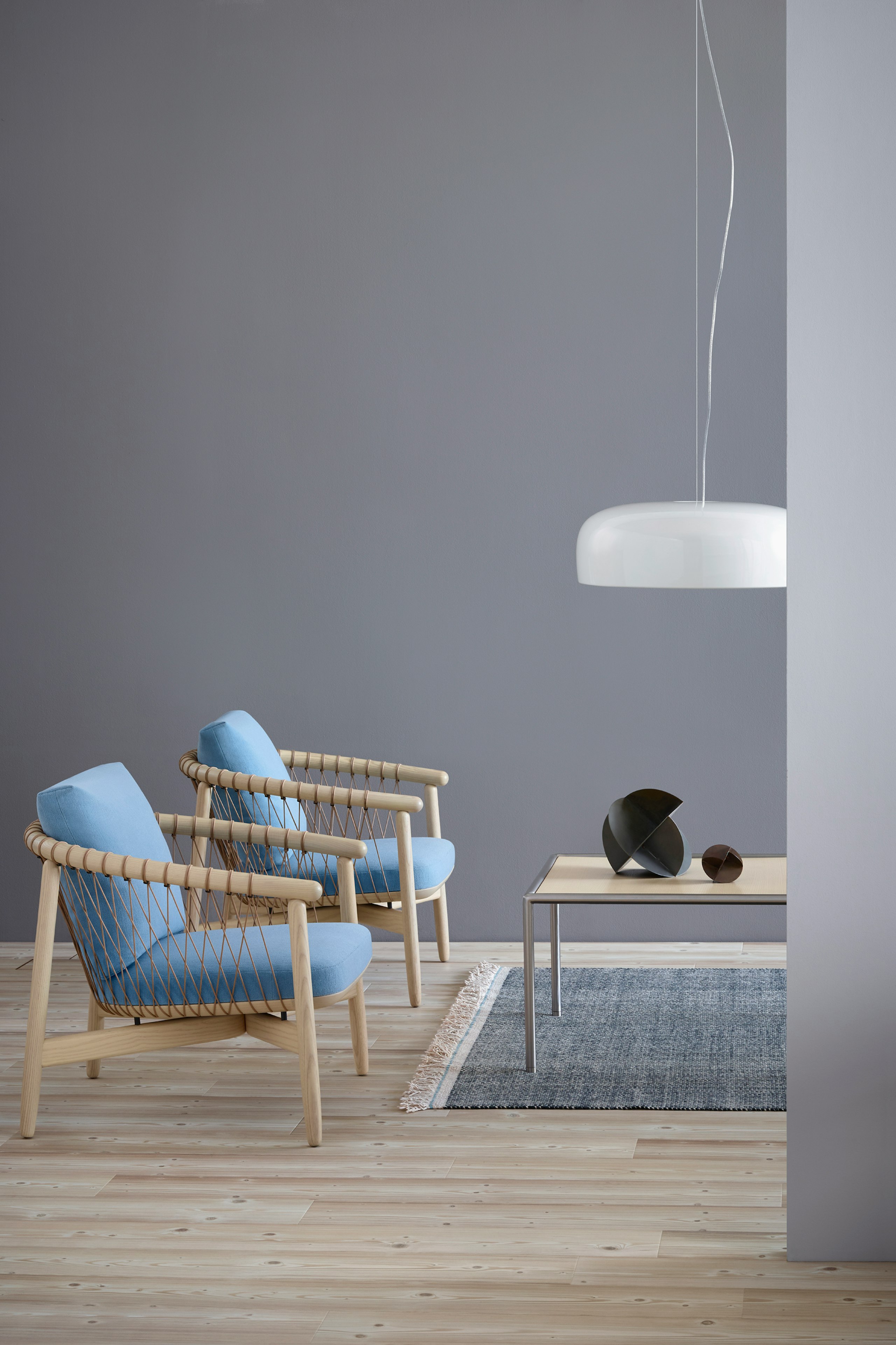 Two Crosshatch lounge chairs with light blue fabric and light wood frames, positioned next to a rectangular Full Round coffee table.