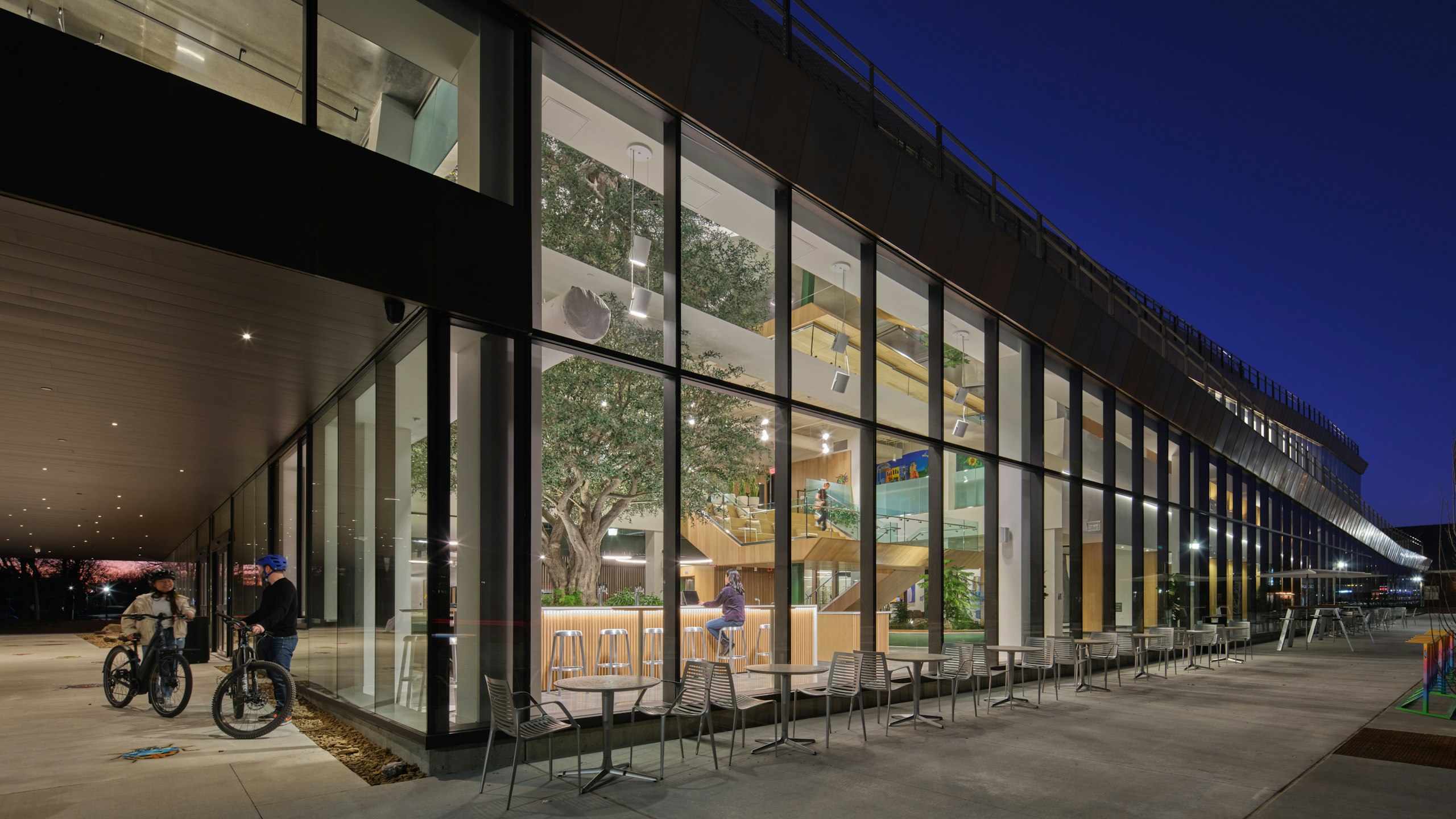 Two people with bikes having a conversation outside the Ledger office space at night