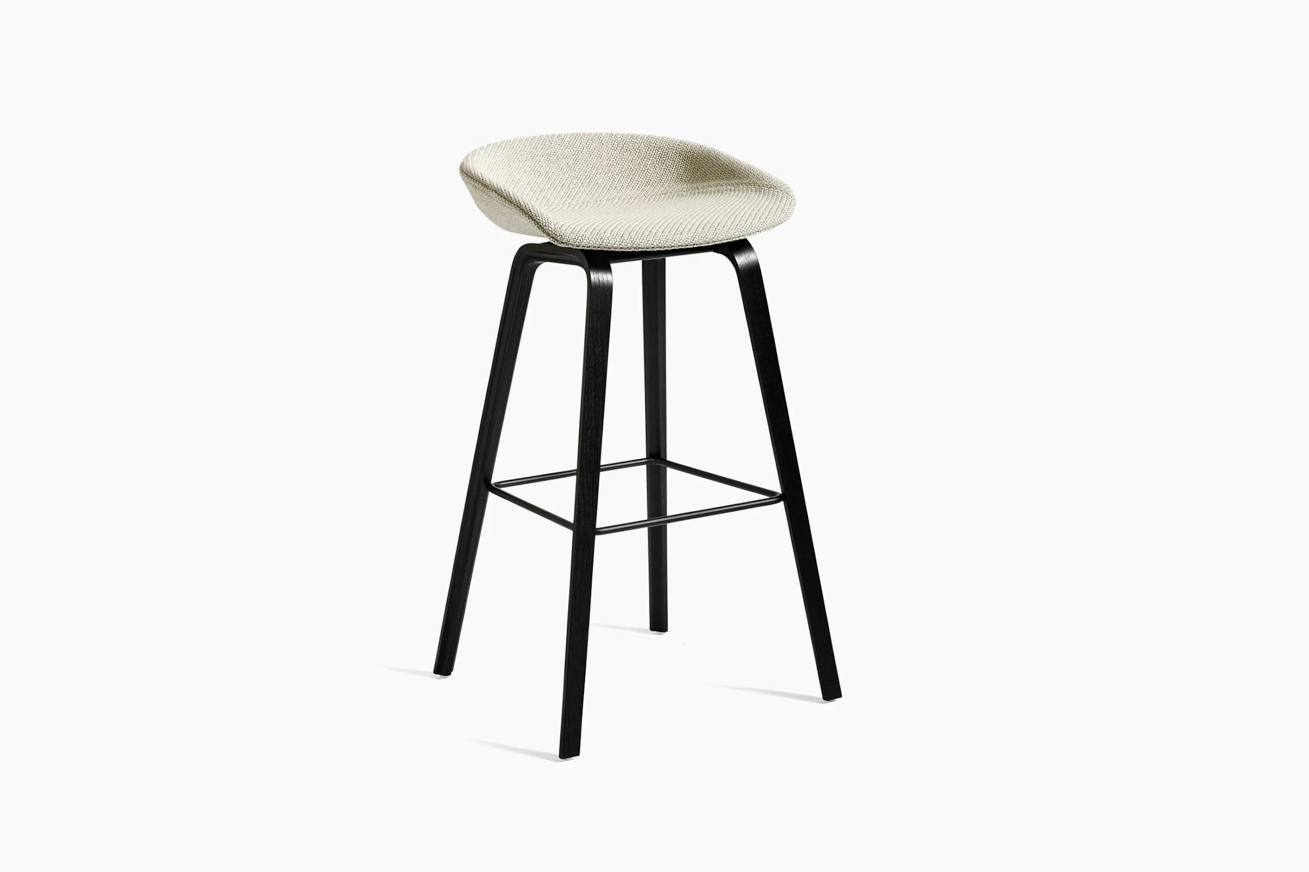 Off-white upholstered About A Stool with black wooden base, viewed at an angle.