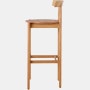 Profile view of an oak bar-height Comma Stool.