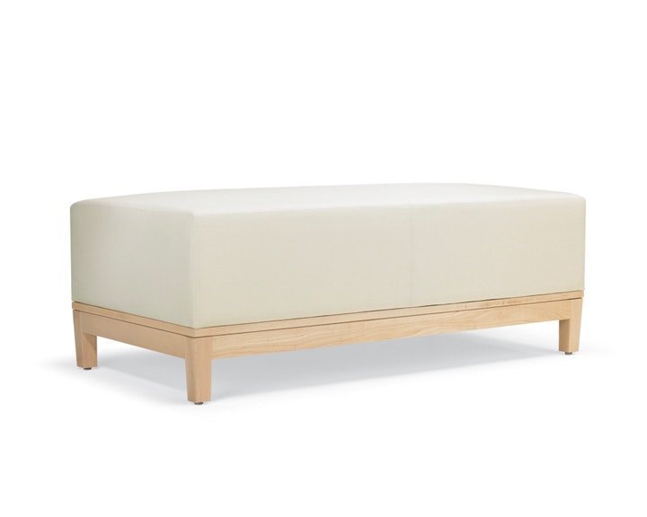 A three-quarter view of a Brava Platform Lounge Bench with maple base and white textile.
