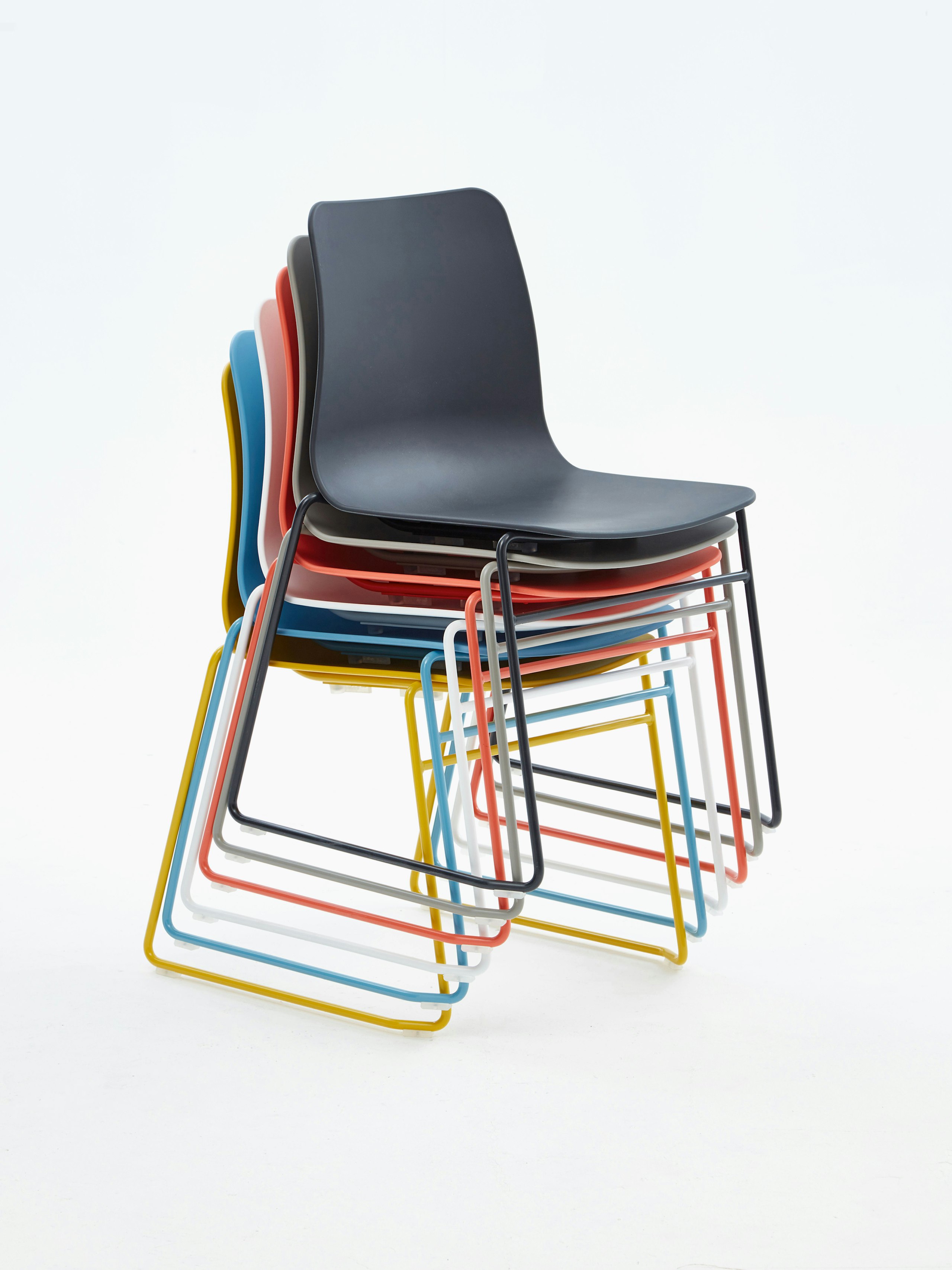 A yellow, blue, white, orange, gray, and black Polly Side Chair stacked ontop of one another, viewed at an angle.