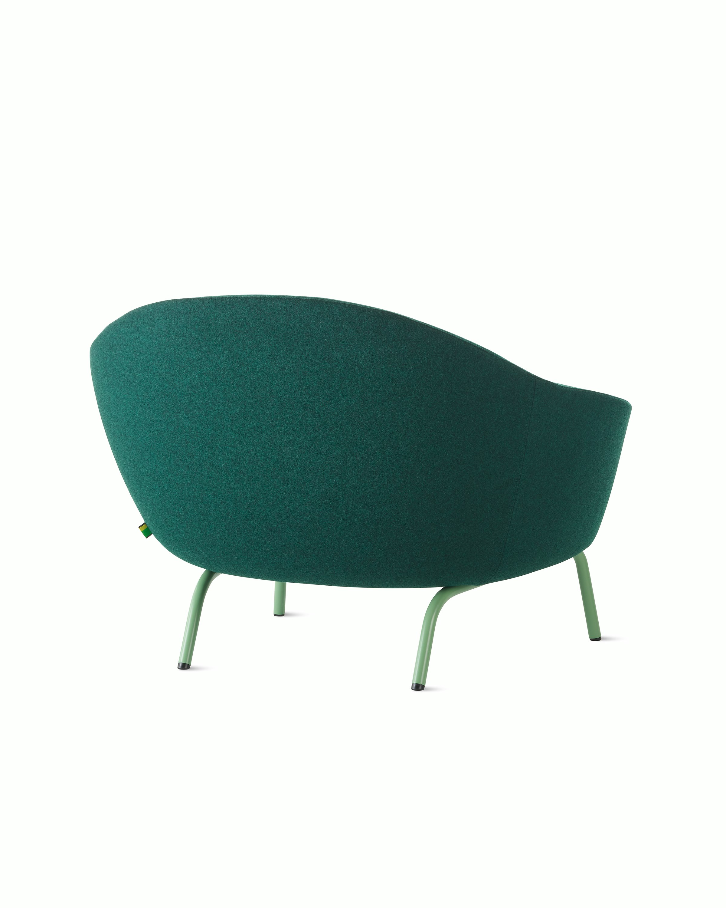 White sweep shot of dark green upholstered Ever armchair on pale green steel legs.