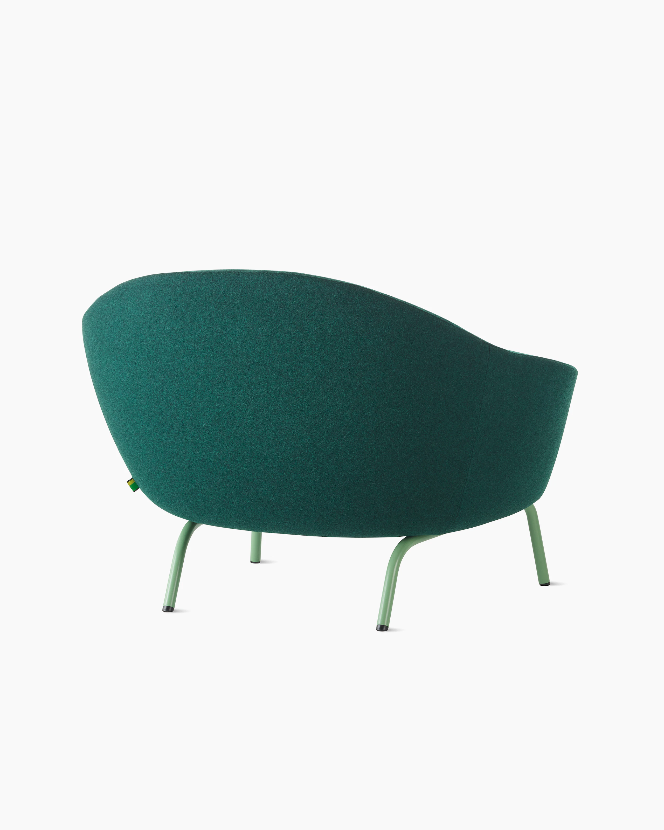 White sweep shot of dark green upholstered Ever armchair on pale green steel legs.
