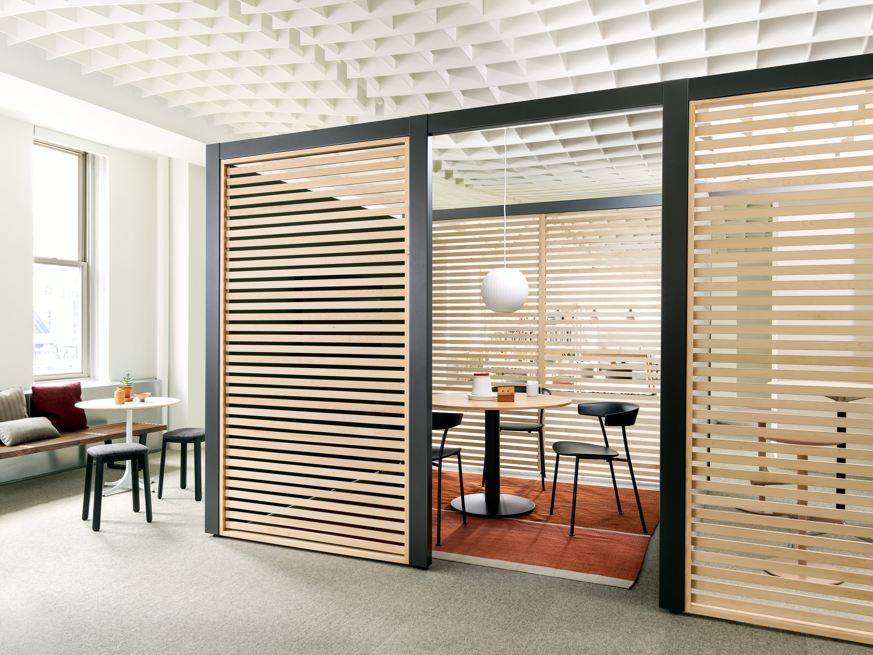 Overlay work area featuring light-colored wood slats and small table with three black Leeway Chairs.