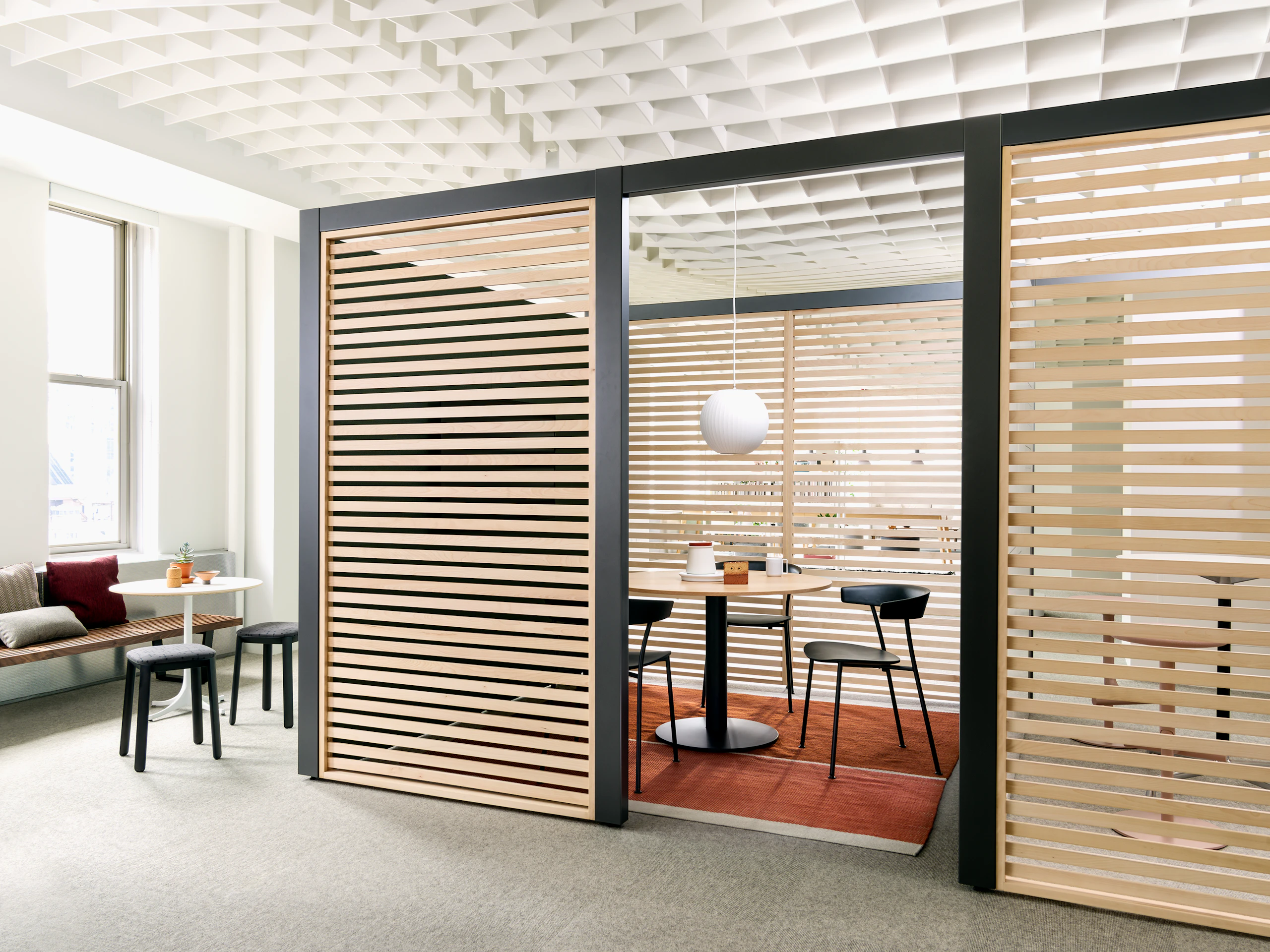Overlay work area featuring light-colored wood slats and small table with three black Leeway Chairs.