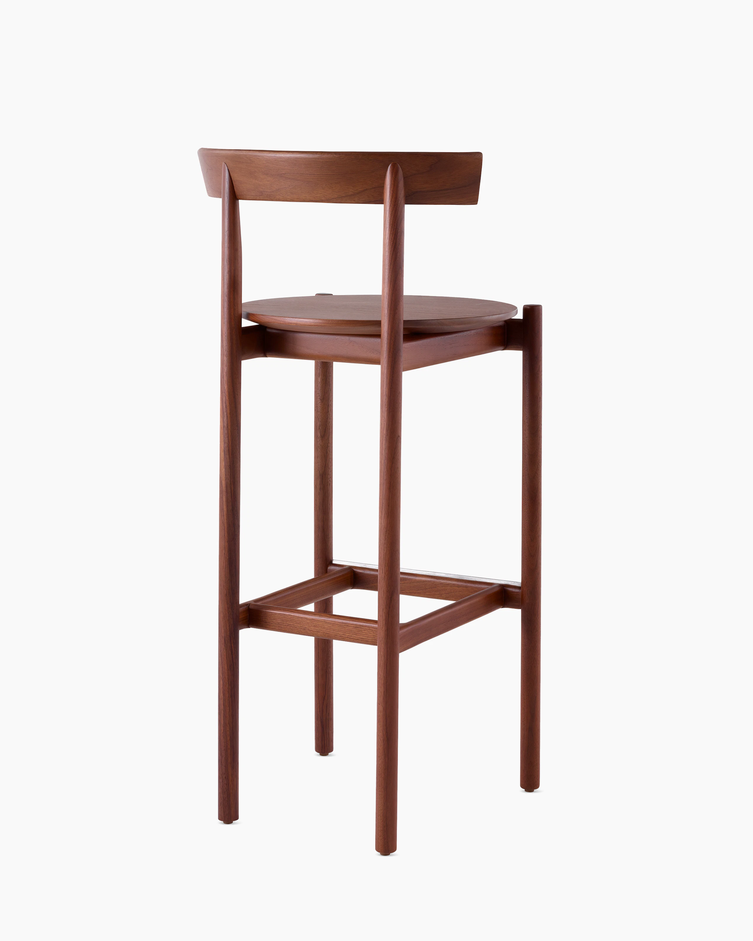 A walnut bar-height Comma Stool, viewed from the back at an angle.