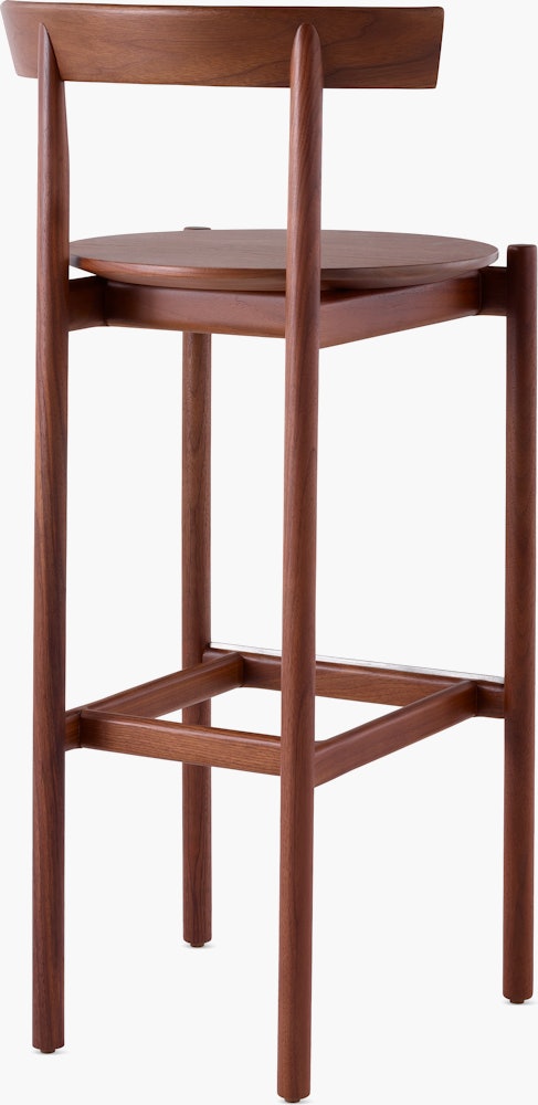 A walnut bar-height Comma Stool, viewed from the back at an angle.