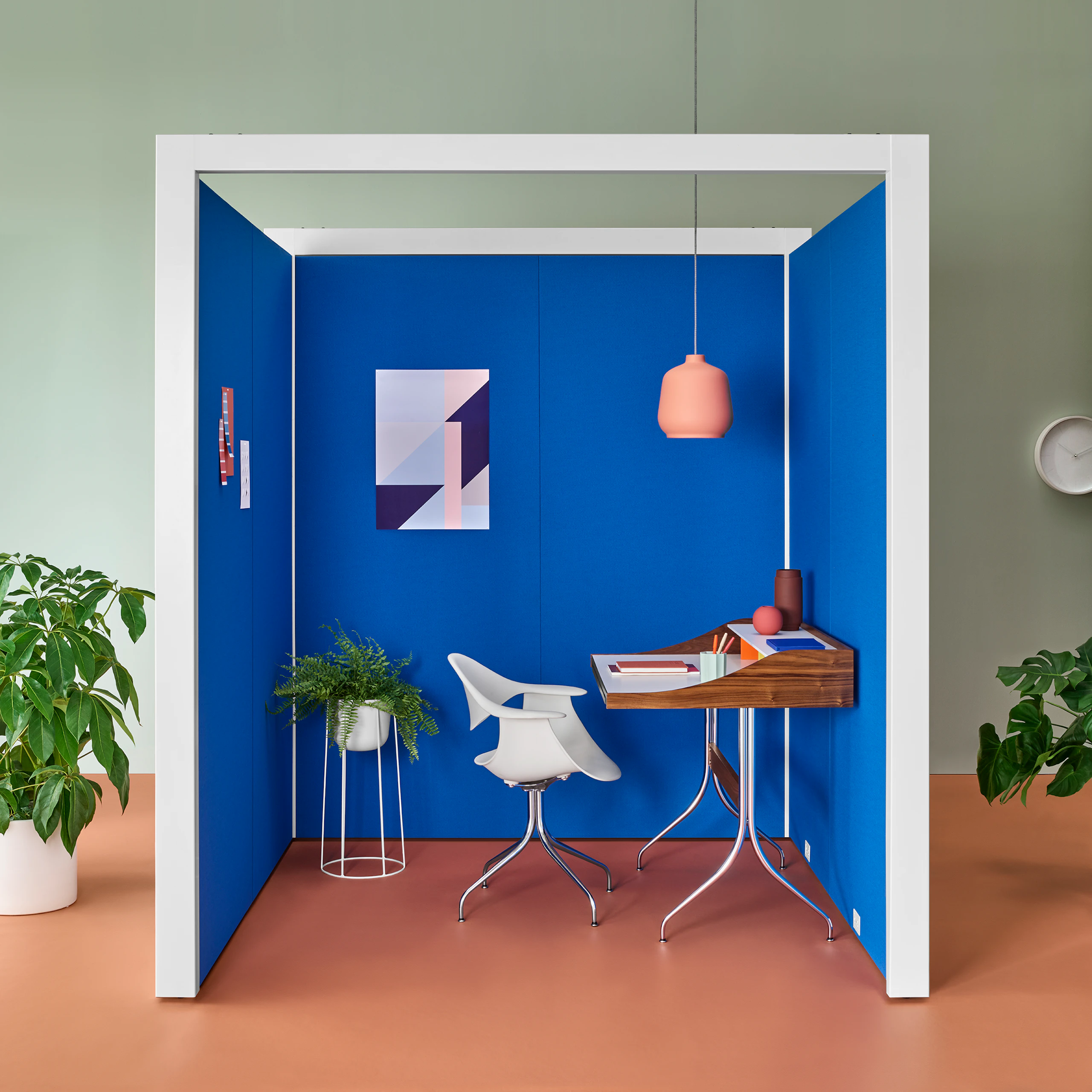 A three-sided Overlay space with blue tackable fabric interiors and white structure. A chair, desk and a hanging lamp are inside Overlay.