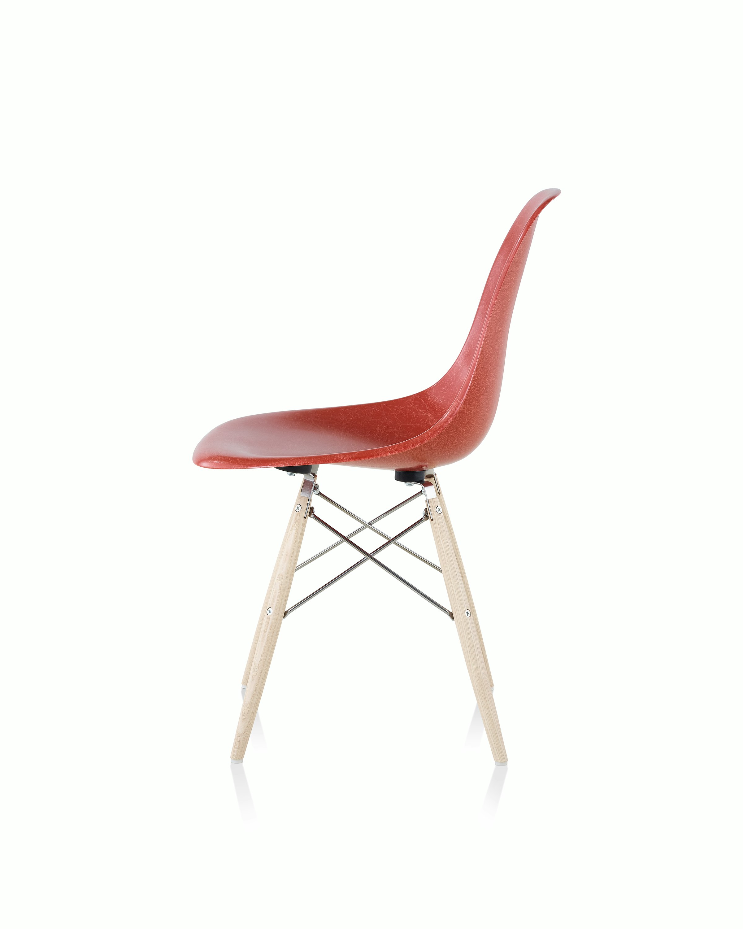 An Eames Molded Fibrglass Side Chair with a dowel base and red seat, viewed from the side.