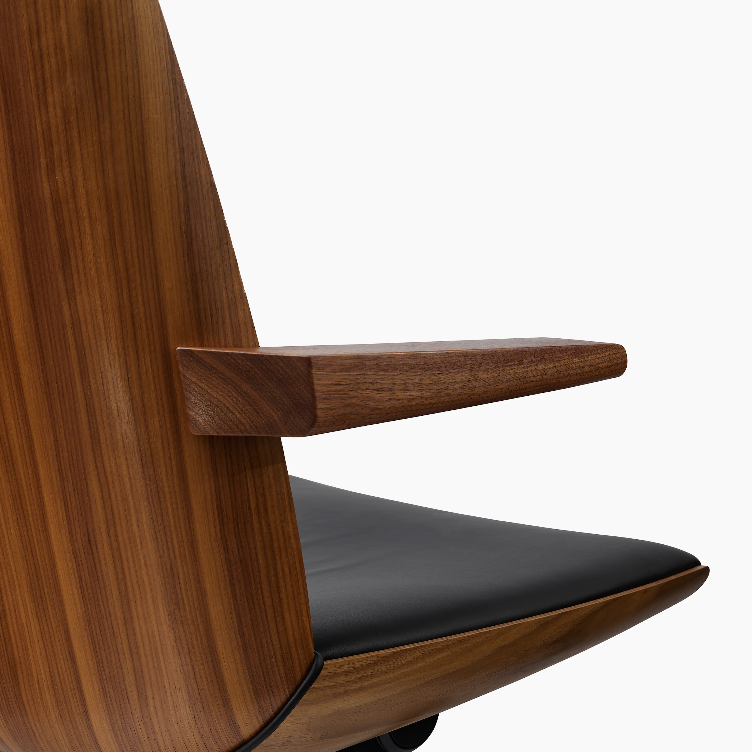 Detail view of a Clamshell Chair with a Sundance Walnut shell upholstered with Bristol Leather in Black, viewed from behind at an angle.