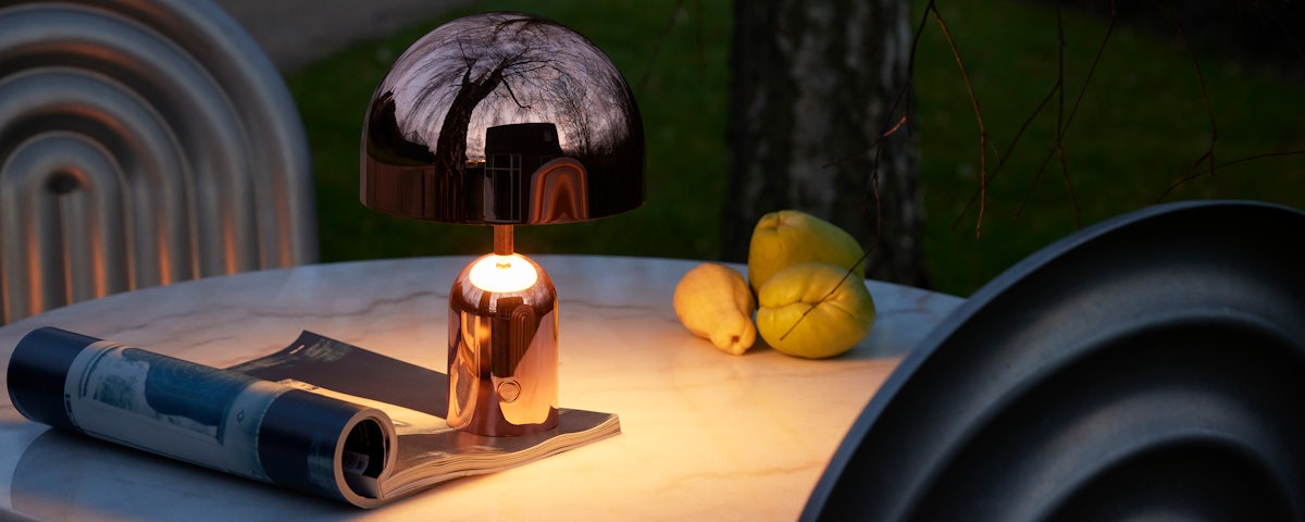 Bell Portable Lamp in Copper on an outdoor cafe table