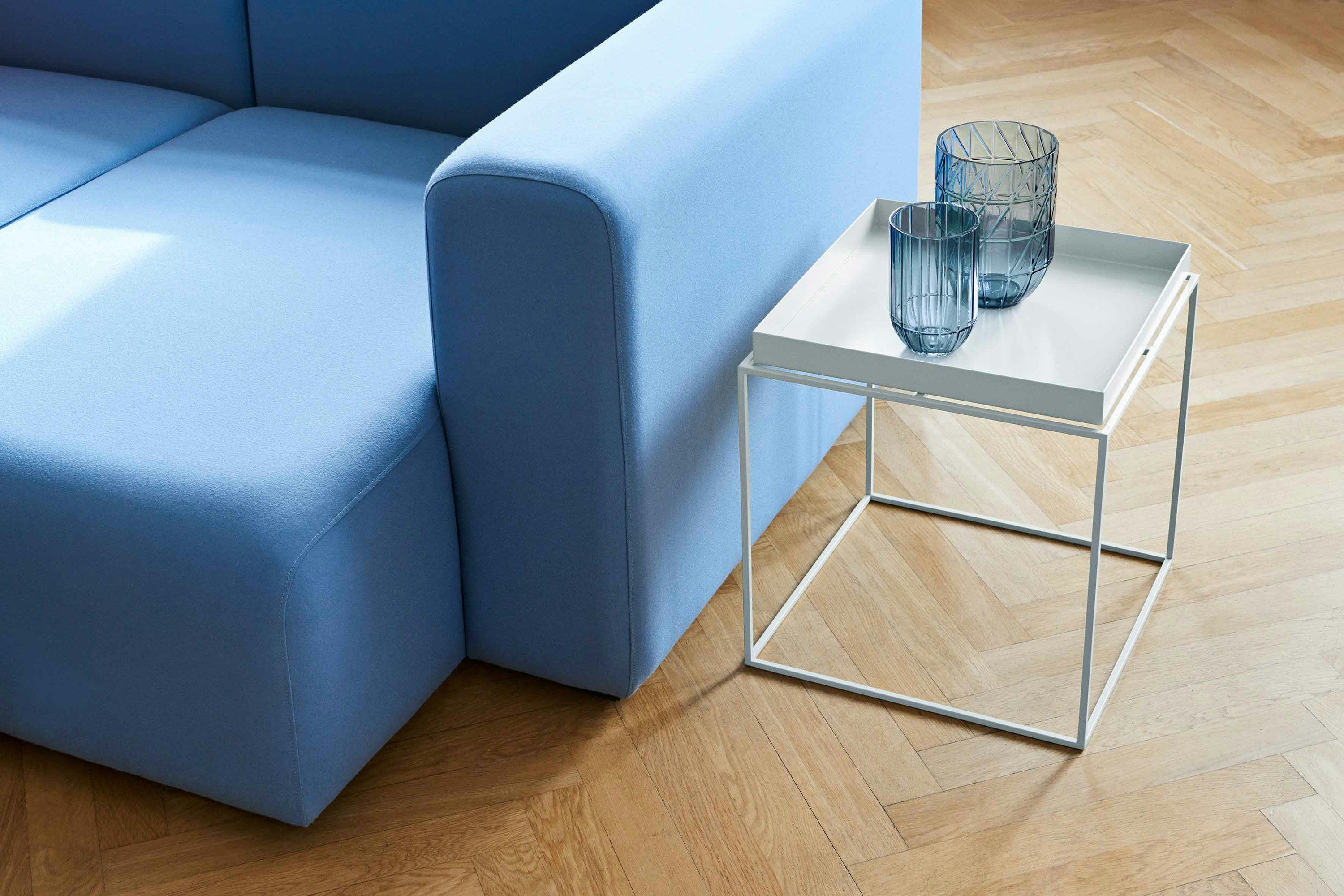 White, square Tray Side Table alongside light blue Mags Sectional Sofa.