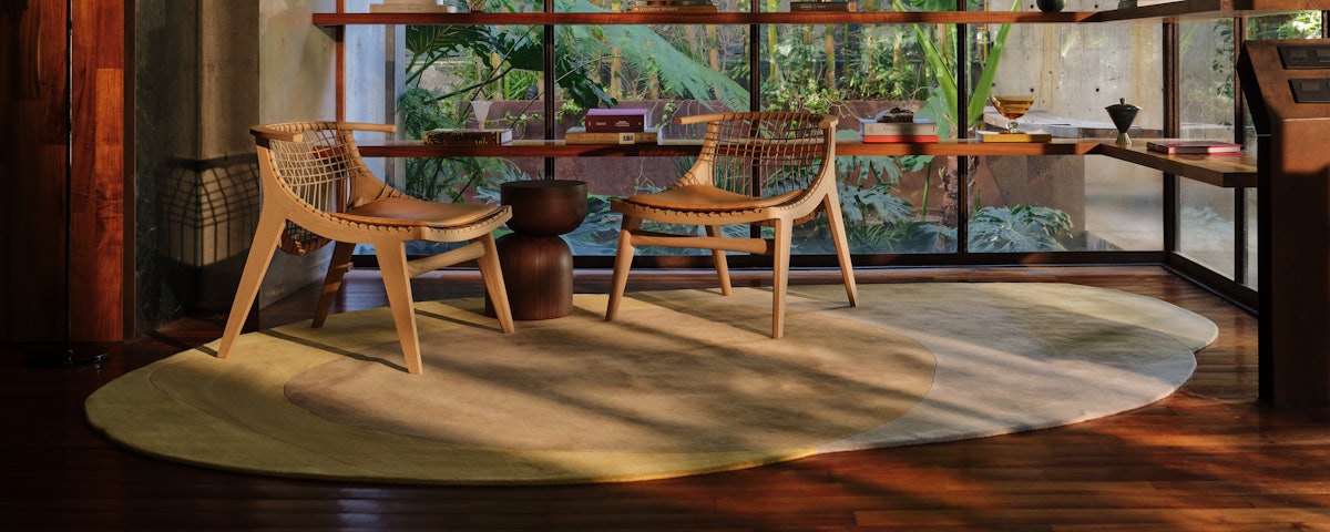 Two Klismos Lounge Chairs on a Layers Rug in a living room setting