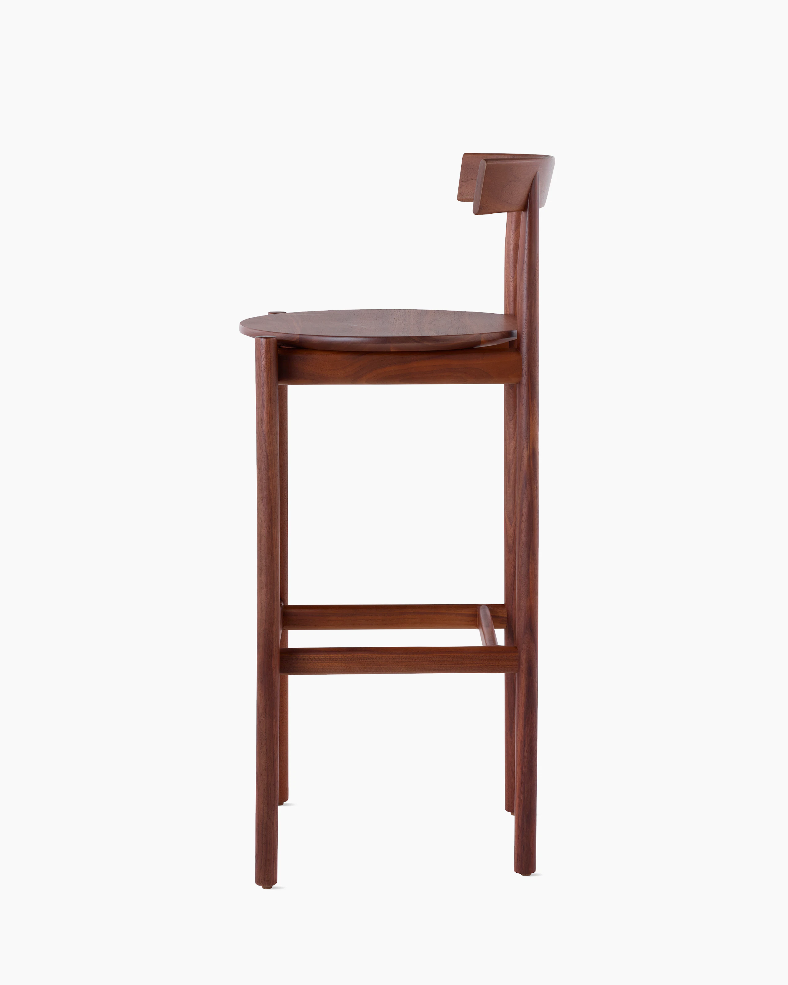 Profile view of a walnut bar-height Comma Stool.