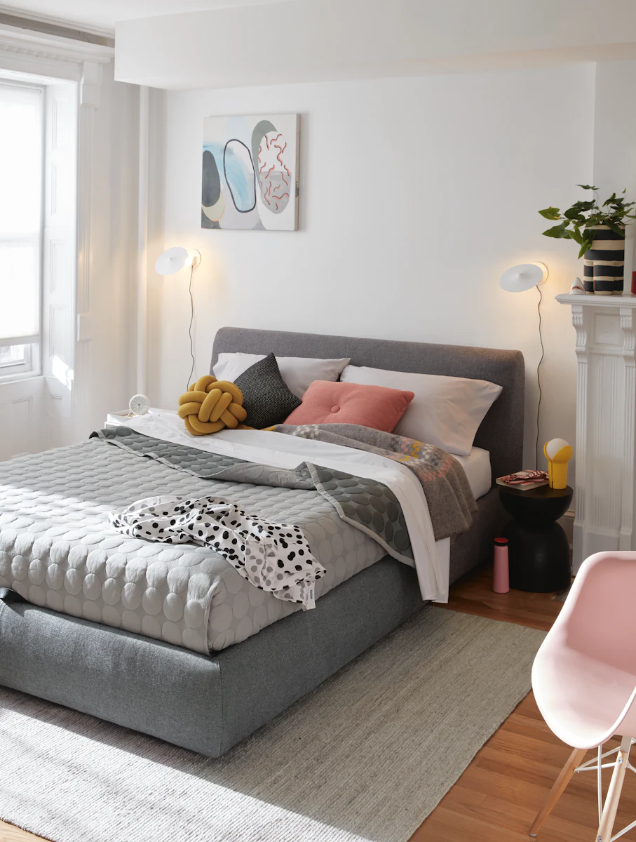 Side view of a dark fabric upholstered bed with white bedding