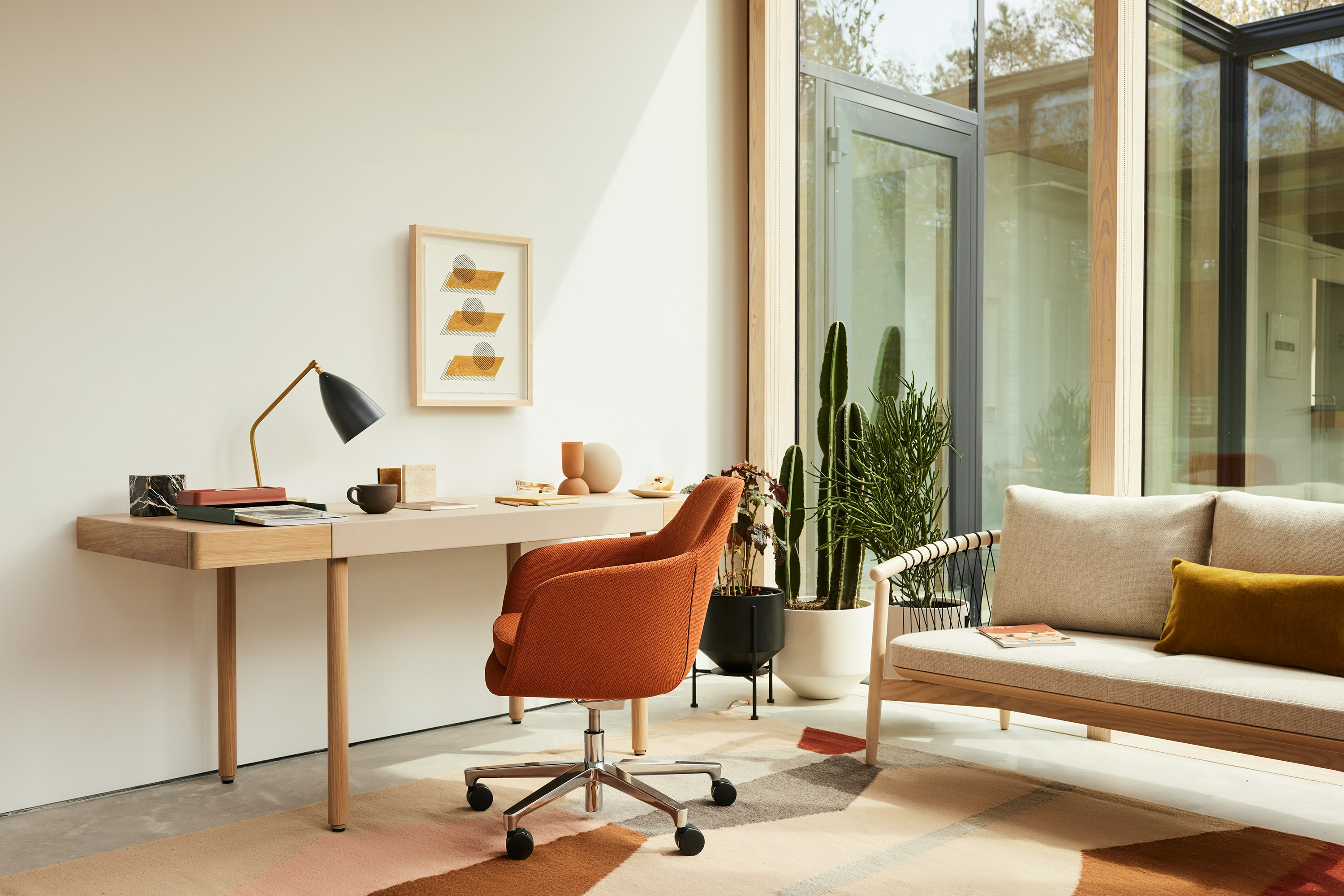 A home office setting with the New Canaan Leatherwrap Sit-to-Stand Desk, Saiba office chair and Crosshatch Settee.