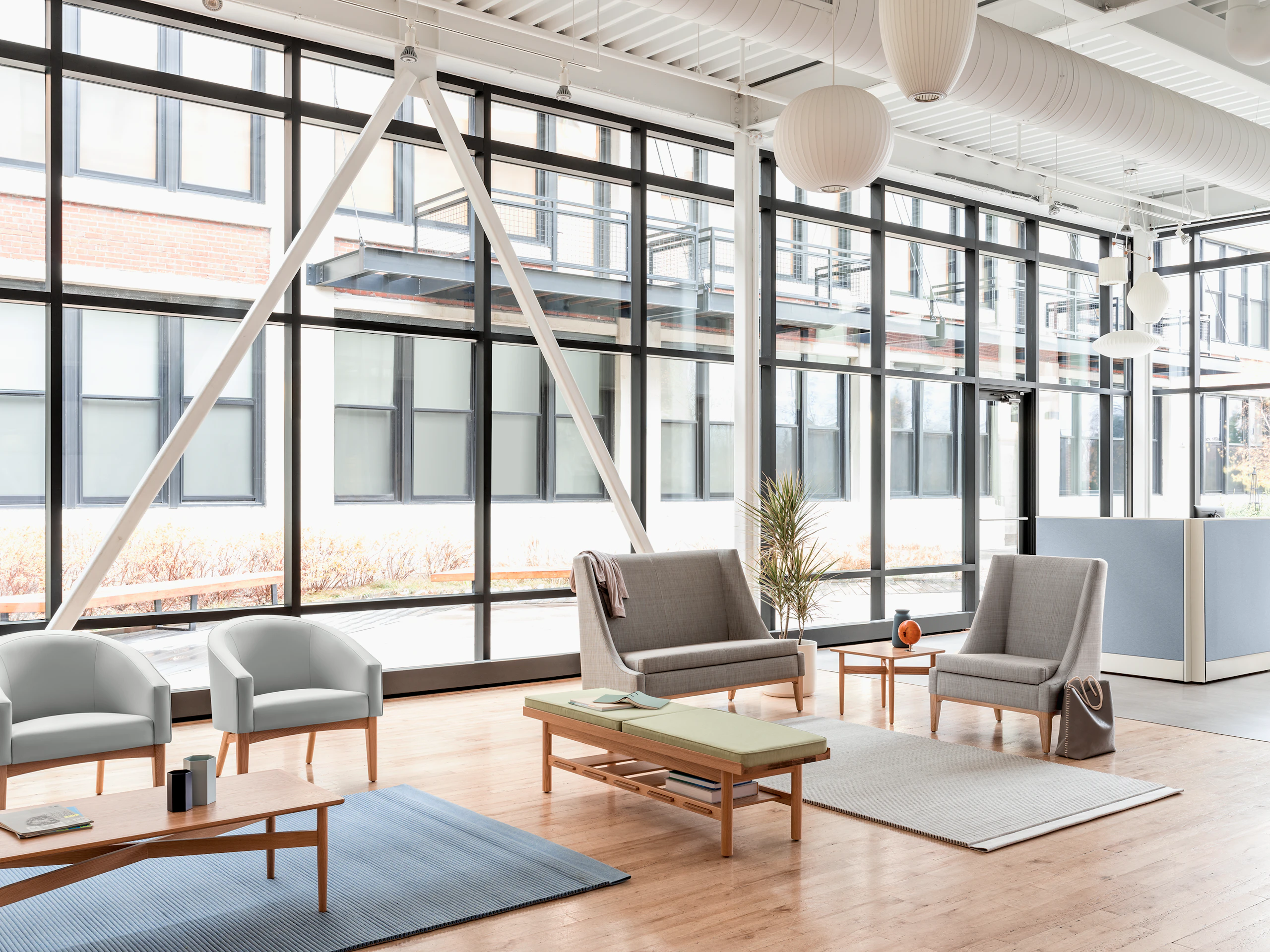 A window filled waiting area featuring a Nemschoff Iris Settee, Nemschoff Sophora Lounge Chairs, and a Nemschoff Tamarack Table and Bench.