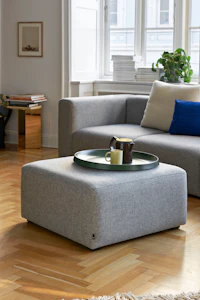 Grey Mags Ottoman, viewed at an angle in front of a grey Mags Sectional Sofa.