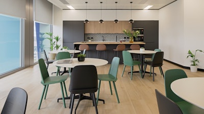 A communal kitchen space at the NATO Defence Innovation Accelerator in London furnished with green and black chairs, round Civic tables, and bar-height stools at a kitchen island