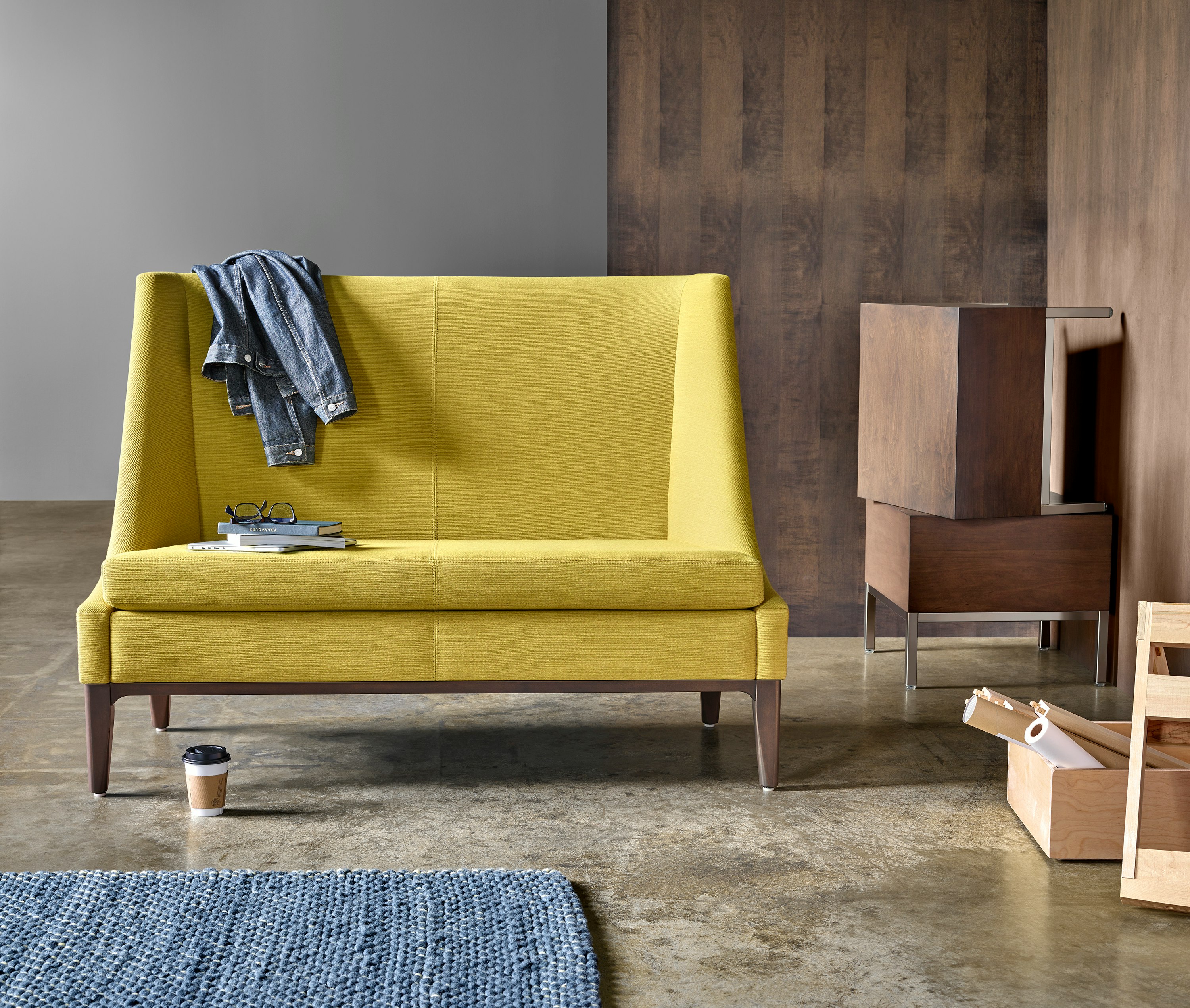 Nemschoff Iris Settee in yellow upholstery in a room with a cement floor and dark wood walls.