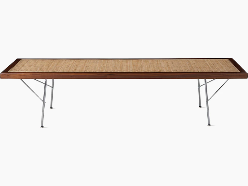 A Nelson Cane Bench with a walnut frame and metal legs, viewed from the side.