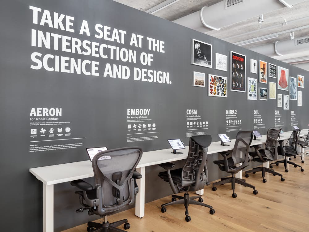 A row of gray office chairs including Aeron, Embody, Cosm, and Mirra 2, line the Performance Seating display in the Fulton Market Showroom.
