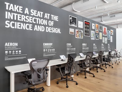 A row of gray office chairs including Aeron, Embody, Cosm, and Mirra 2, line the Performance Seating display in the Fulton Market Showroom.