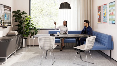 A group setting featuring two people sitting on a blue corner bench while participating in a virtual meeting in a conference room furnished with Geiger Tuxedo Component Lounge seating, a Knoll Grasshopper Table, and a Knoll Florence Knoll Credenza
