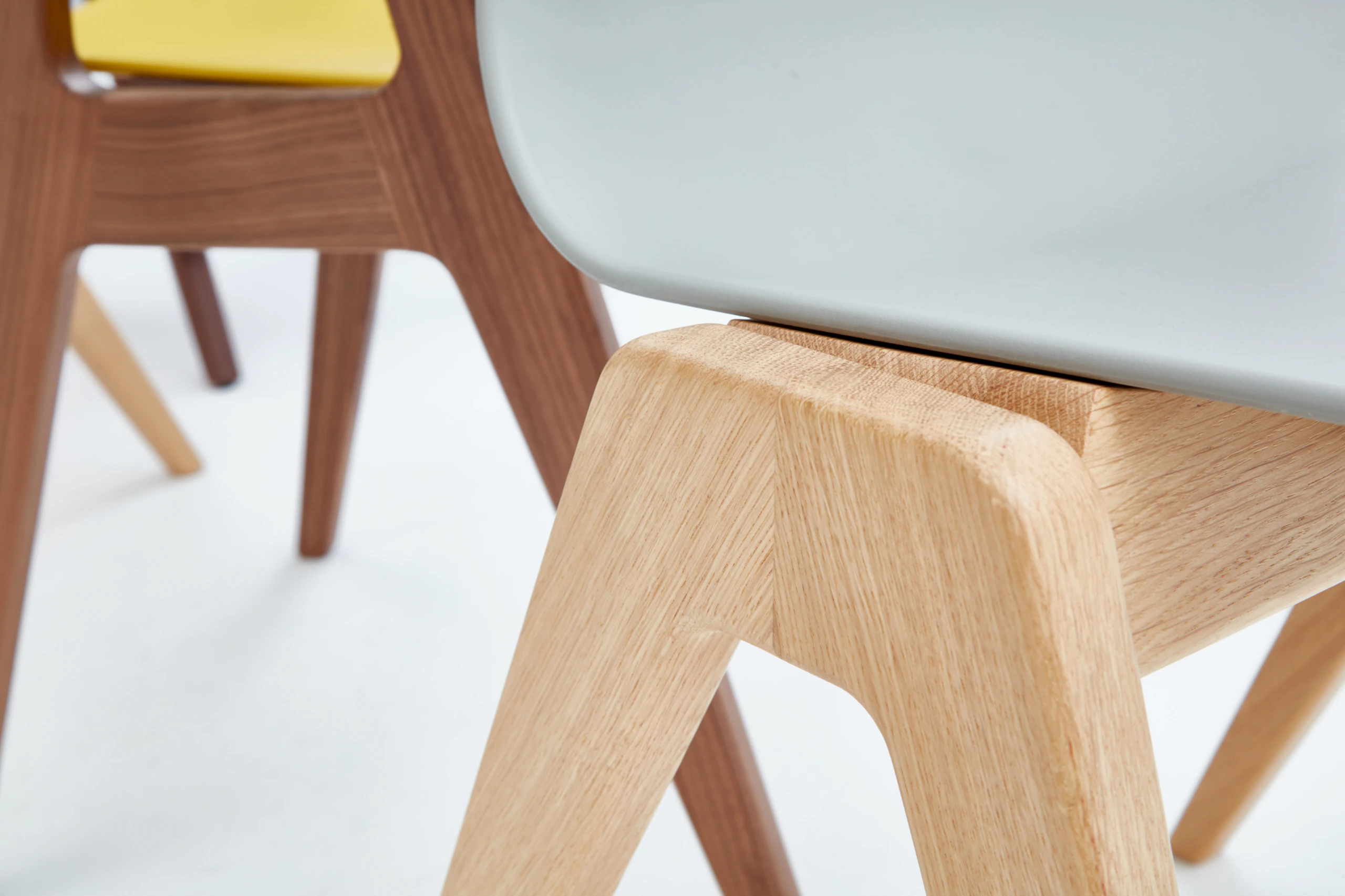 A close-up view of the oak base on a gray naughtone Polly Wood Chair.