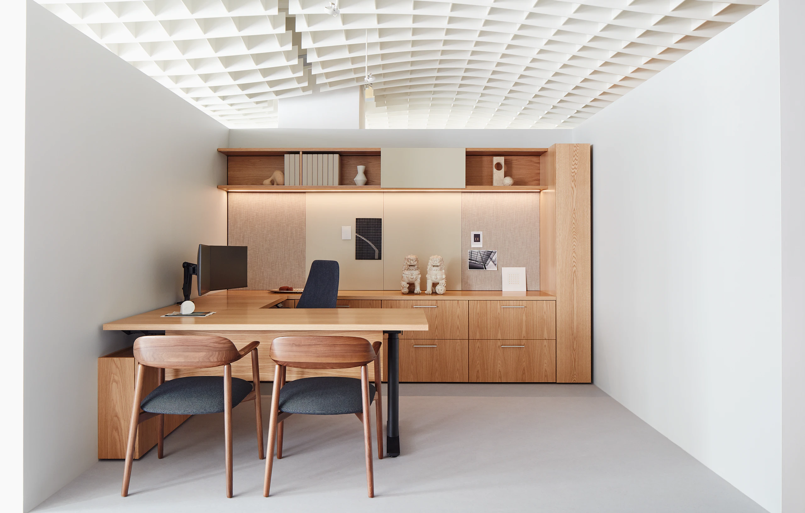 A private office vignette in the Geiger showroom, featuring Geiger One Casegoods with matte sand backpainted glass, a Taper Chair, and Crosshatch Side Chairs.