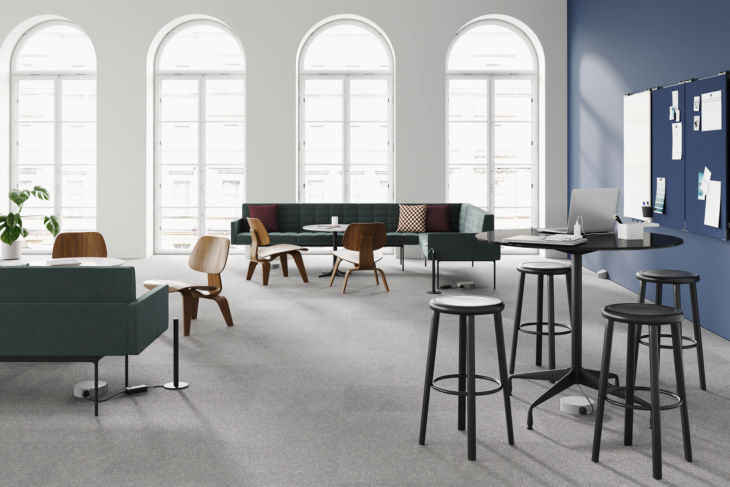 A group of Eames Molded Plywood Chairs, Tuxedo Sofas, and Eames Tables fill an open setting with a Logic Micro Tower in the foreground. All products are connected by Logic Reach power.