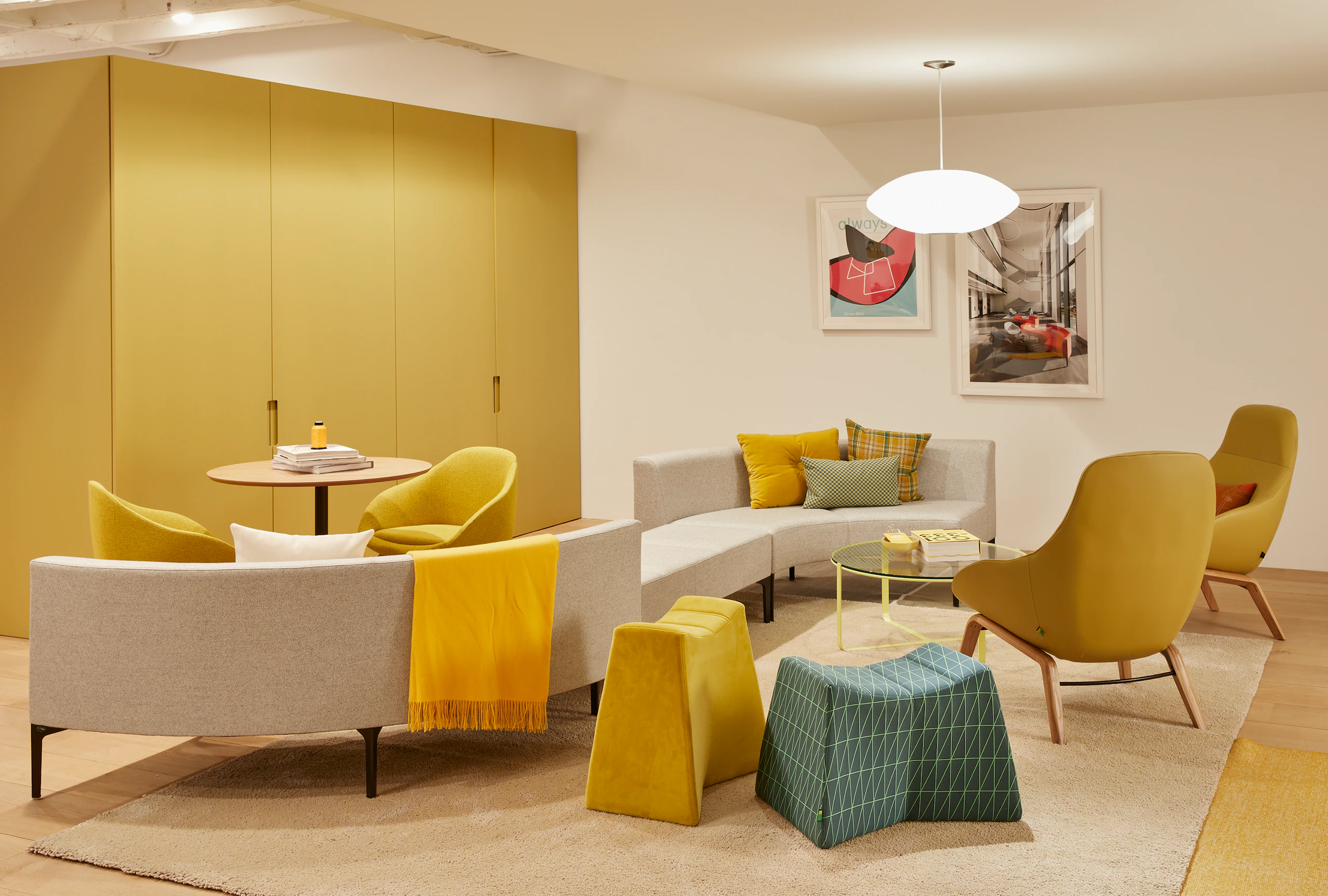An arrangement of yellow Always Lounge Chairs with oak bases, alongside a curved Symbol Sofa and yellow Trace Coffee Tables.